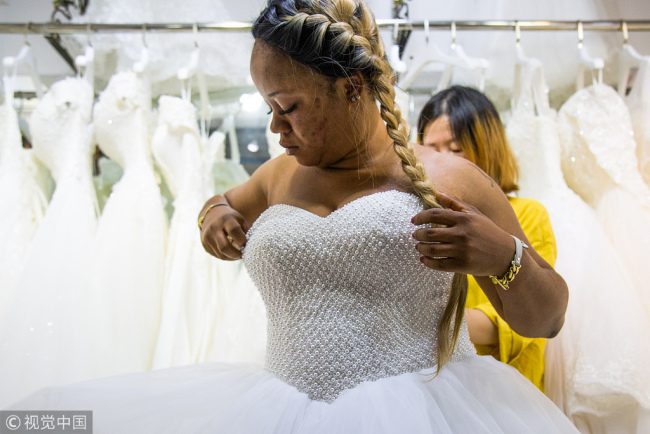 A buyer tries(试穿 shìchuān) on a wedding dress at a wedding-dress market in Guangzhou, Guangdong Province on November 26.[Photo: VCG]