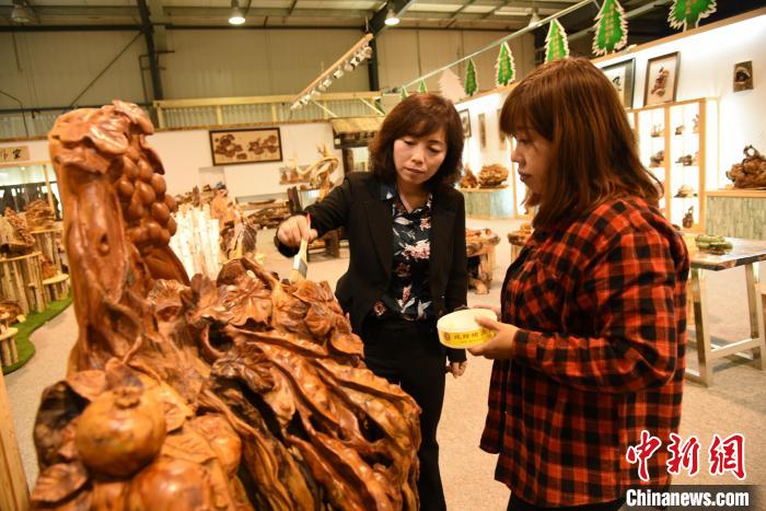 张桂侠(左)介绍木雕产品。　受访者供图